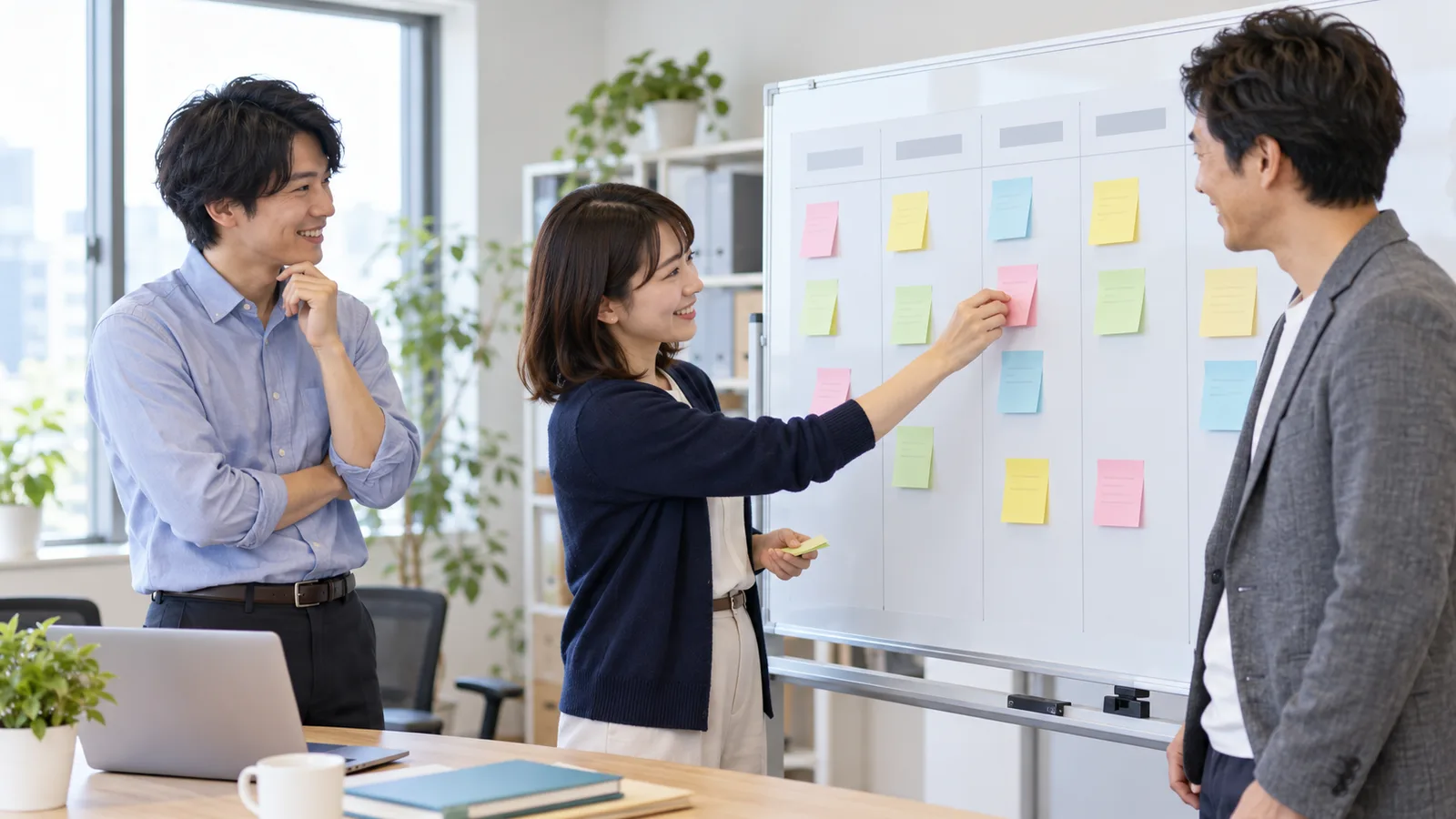 オフィスのホワイトボードに付箋を並べて、3人の社員が投稿の予定を話し合っている様子